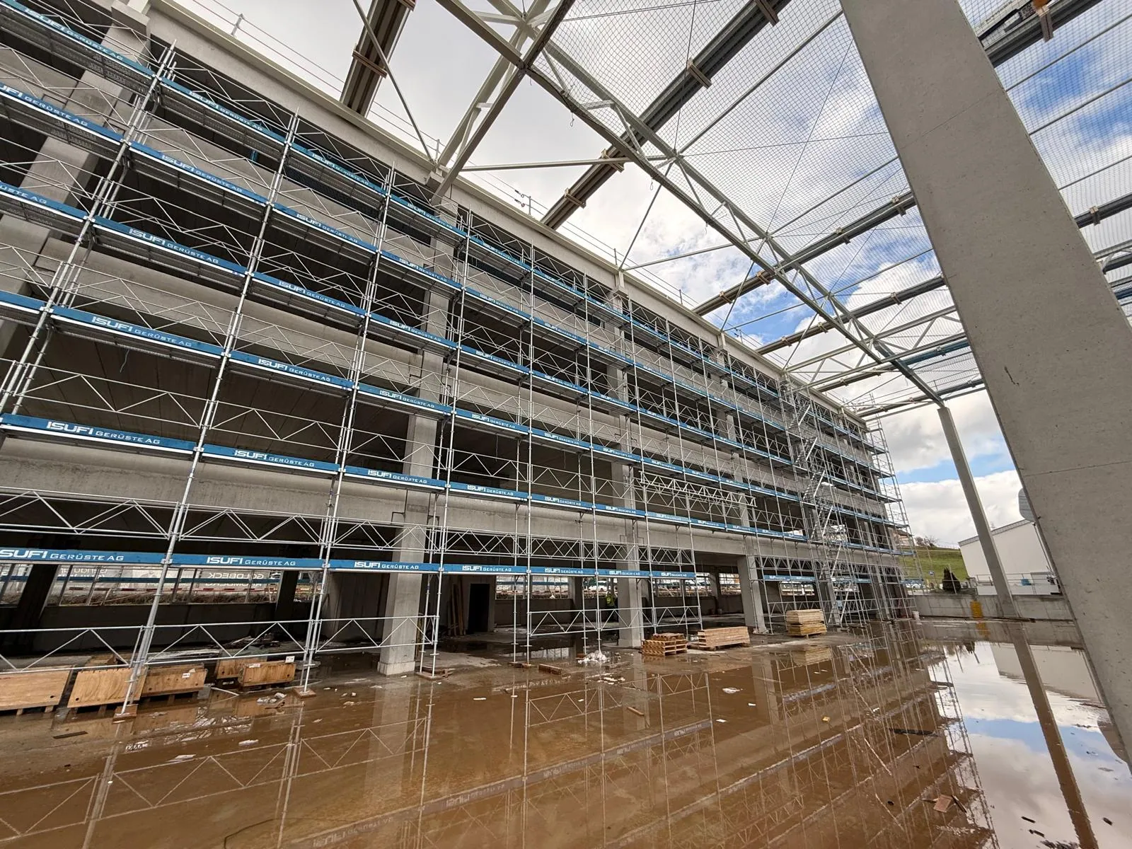 Baugerüst entlang einer Gewerbehalle Baugerüst entlang einer Gewerbehalle. Durchgehende Gerüstbeläge und Seitenschutz ermöglichen Arbeiten an der grossflächigen Hallenfassade. Referenzfoto der Isufi Gerüste AG.